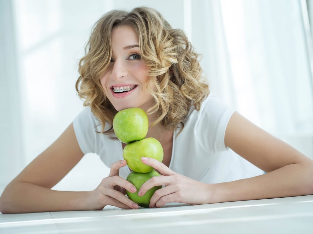 femme avec attaches dentaires tete sur des pommes
